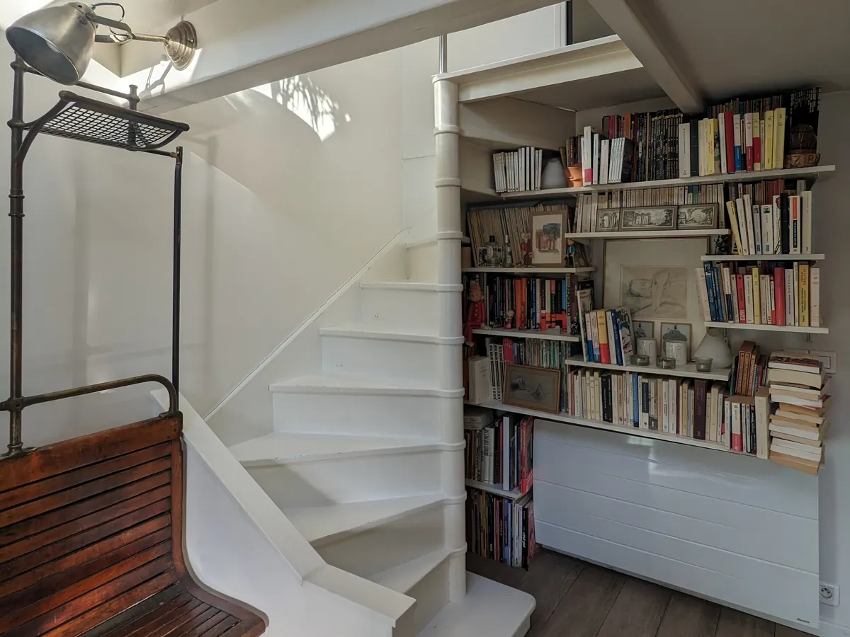 Escalier en colimaçon et bibliothèque dans un duplex sous les toits à Paris